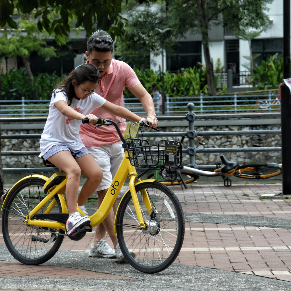 A fater teaching his dauther how to ride a bicycle